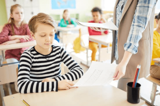 Customized Assessments Teacher handing exams to students