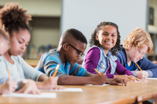 Practice Tests Children writing. One child looking up and smiling